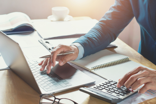 a person using a laptop and a calculator to calculate severance pay