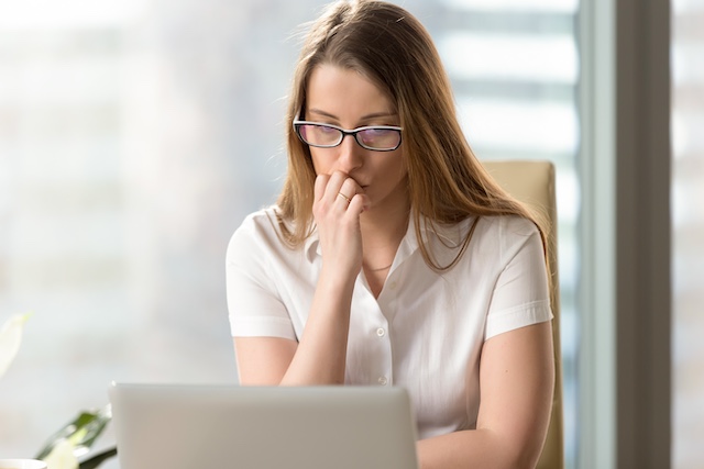 A female employee wearing glasses looks self-consciously at her laptop