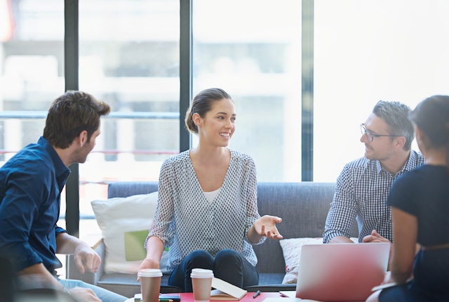 A team of coworkers meet in a casual setting in the office