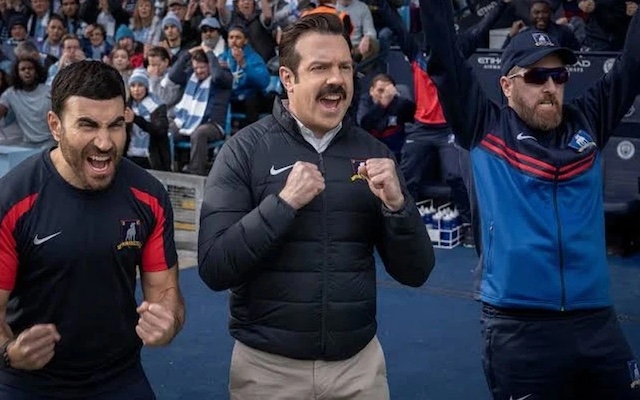 Ted Lasso celebrates on the sidelines with his fellow coaches