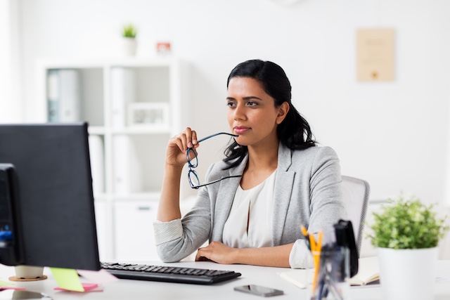 A businesswoman thinks while working at her desk.