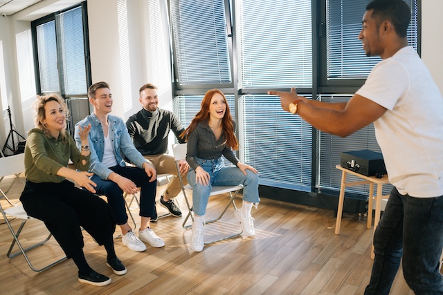 A group of young employees play charades at work