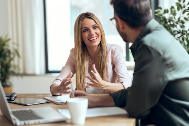 A female manager demonstrates strong people management skills meeting with her male employee