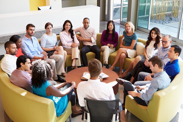 A diverse group of employees meet in a circular setting