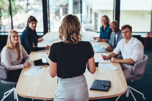 A young Black woman leads her team in a project meeting