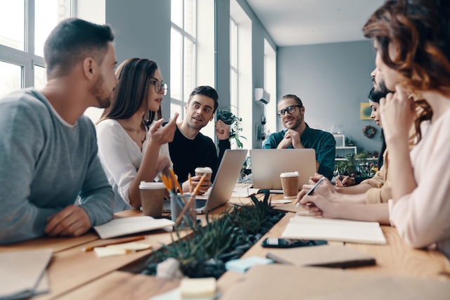 Diverse team of employees brainstorm around a conference table