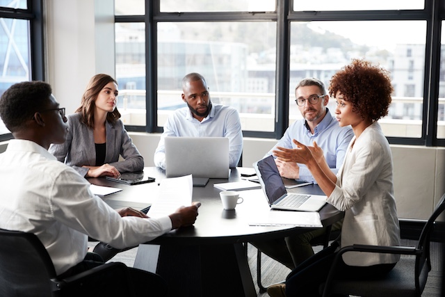 A young Black woman leads her team in a project meeting