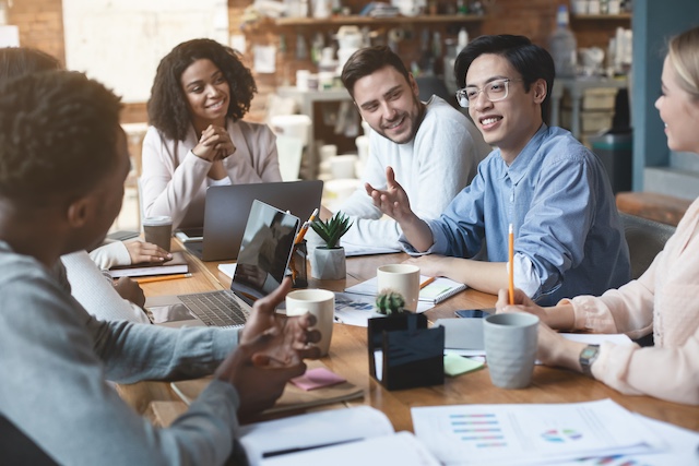 A diverse group of young professionals meet to discuss a project