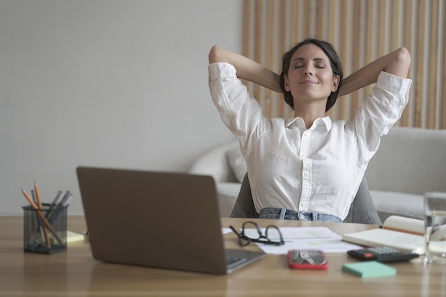 A woman takes a break at her desk in her home office