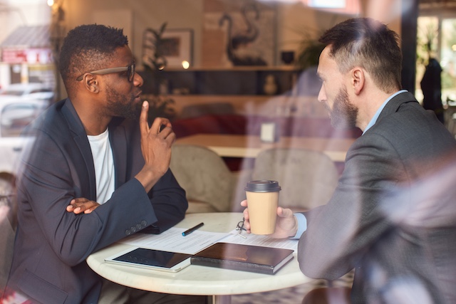 Two businessmen have coffee at a cafe