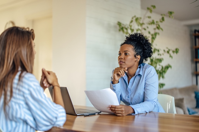 An African-American hiring manager listens thoughtfully to a female candidate during a job interview
