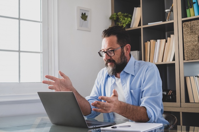 A middle aged man has a video call in his home office