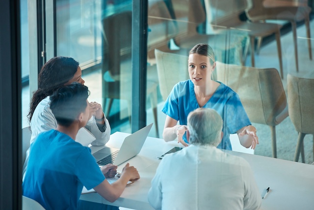 Four medical professionals meet in a conference room