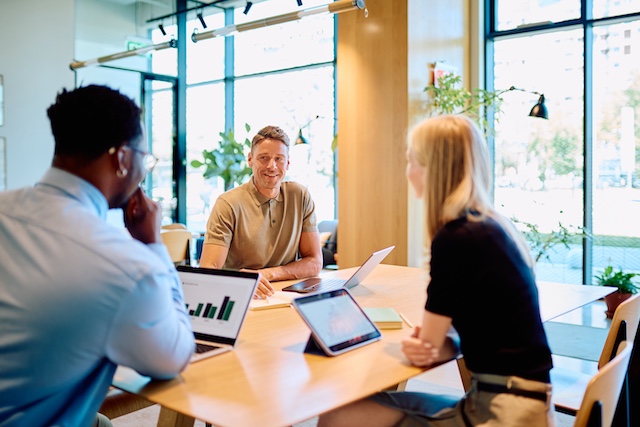 A team of managers meet in a bright windowed conference room