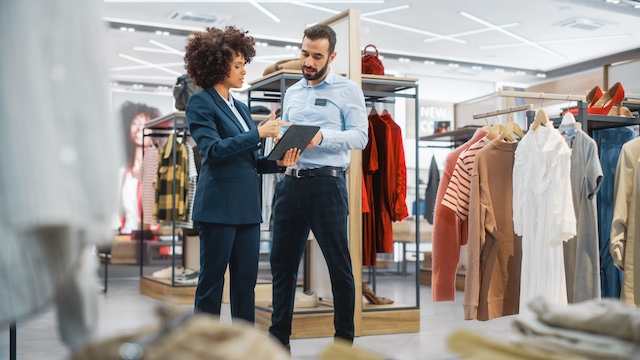 A female retail manager goes over numbers with a male sales associate on the sales floor of a store
