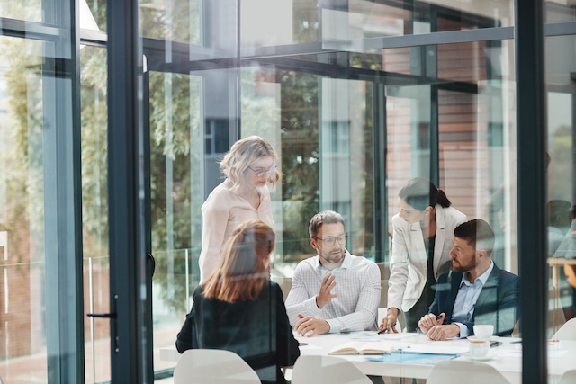 Four executives meet in a windowed conference room